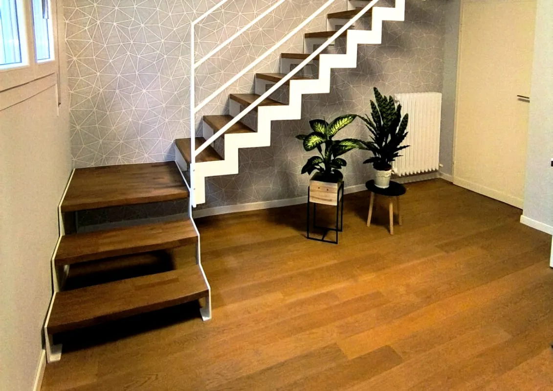 Scala con struttura in taglio laser portante in acciaio verniciato con gradini in faggio lamellare con tinta simile al parquet