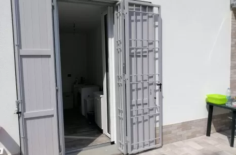 Infisso aperto in acciaio zincato e verniciato a polvere in forno con ante scorrevoli e lamelle fisse.