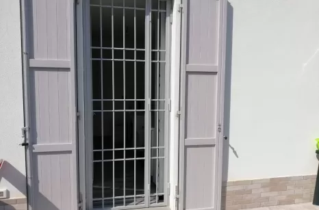 Infisso in acciaio zincato e verniciato a polvere in forno con ante scorrevoli e lamelle fisse.