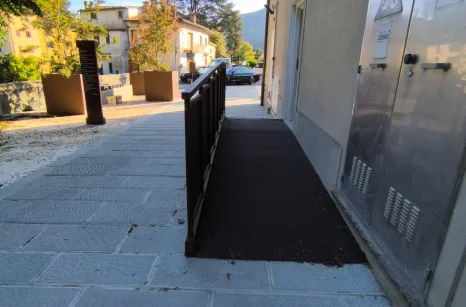 Rampa disabili in acciaio verniciato simil corten con pavimento in lamiera stirata antiscivolo e balaustra con pannelli in lamiera forata