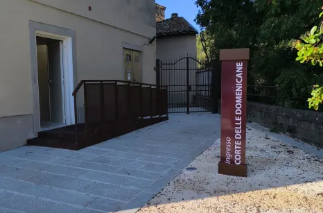 Rampa disabili in acciaio verniciato simil corten con pavimento in lamiera stirata antiscivolo e balaustra con pannelli in lamiera forata