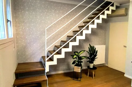 Scala con struttura in taglio laser portante in acciaio verniciato con gradini in faggio lamellare con tinta simile al parquet