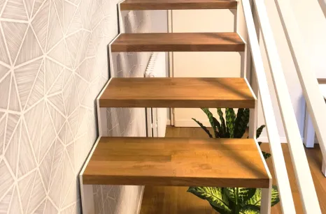 Scala con struttura in taglio laser portante in acciaio verniciato con gradini in faggio lamellare con tinta simile al parquet