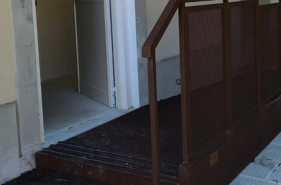 Rampa disabili in acciaio verniciato simil corten con pavimento in lamiera stirata antiscivolo e balaustra con pannelli in lamiera forata